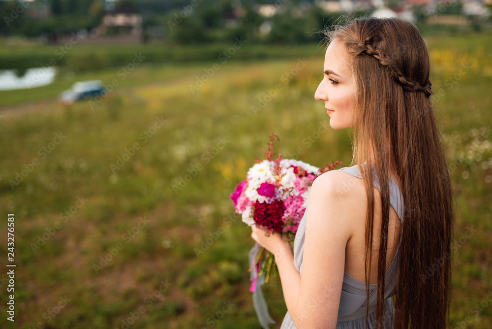 Fototapeta premium Happy bride in beautiful white dress posing with bouquet of flowers on summer day. Wedding street photo session. Beautiful cheerful lifestyle portrait of bride