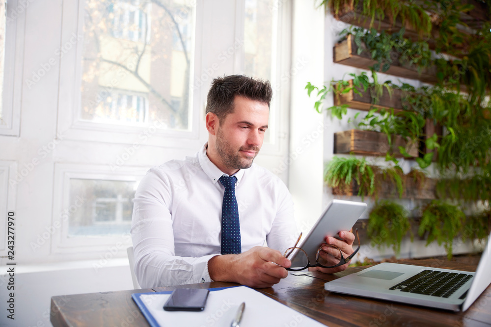 Businessman working on digital tablet while sitting at office desk Businessman working on digital tablet while sitting at office desk
