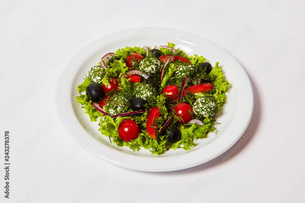 Italian cheese balls salad with tomatoes and fresh vegetables on the plate. Isolated on the white background Italian cheese balls salad with tomatoes and fresh vegetables on the plate. Isolated on the white background