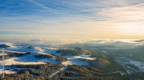 Aerial view of a gold sunset over winter snow.