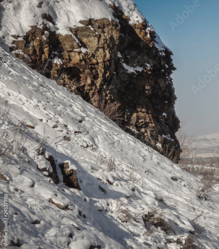 Winter landscape. Rocky snow cliff. Kazakhstan. Blue sky. Winter. Natural scenery