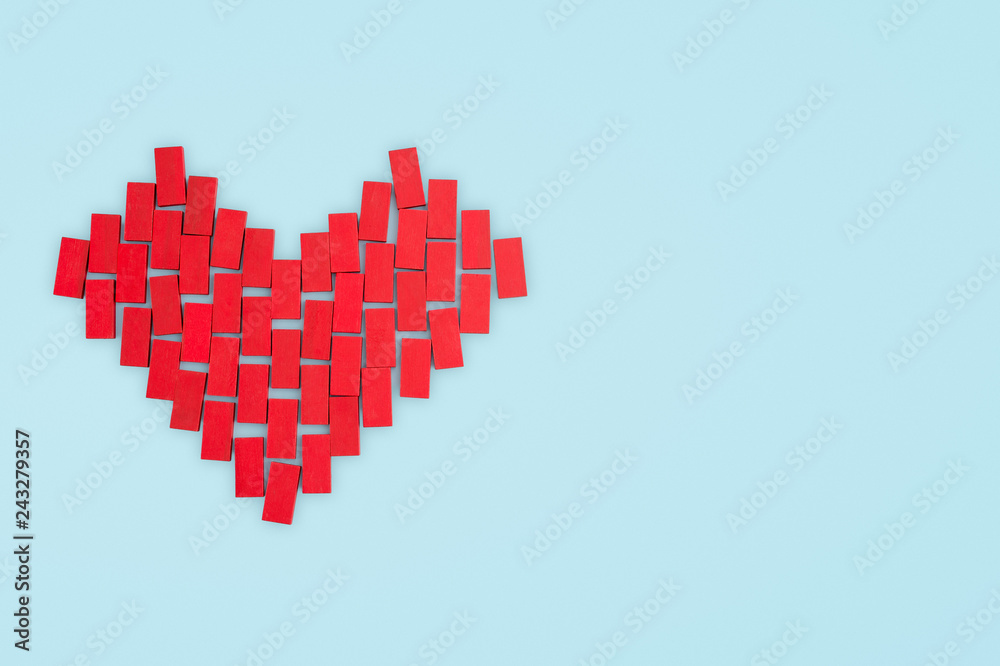 Fototapeta premium Love concept. Red heart made of toy blocks on a blue background.