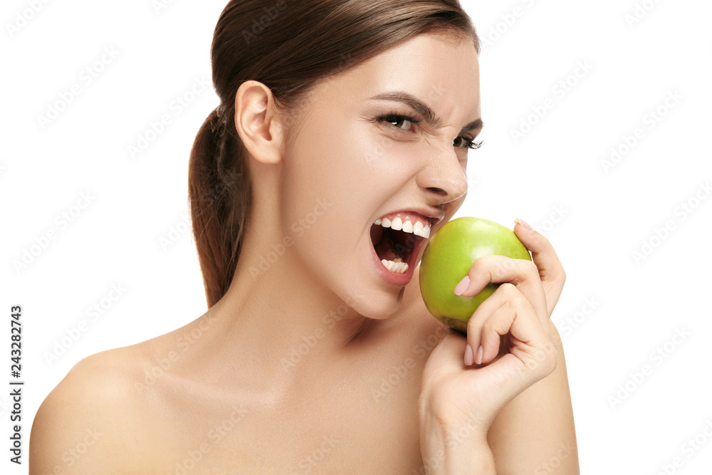 The portrait of attractive caucasian smiling woman isolated on white studio background with green apple fruits The portrait of attractive caucasian smiling woman isolated on white studio background with green apple fruits
