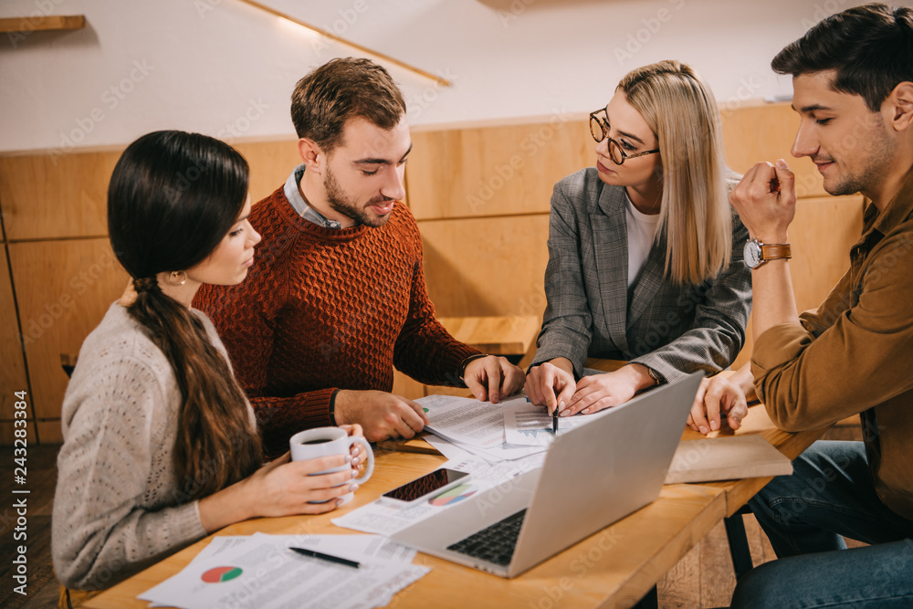 group of coworkers looking at charts and graphs in cafe group of coworkers looking at charts and graphs in cafe
