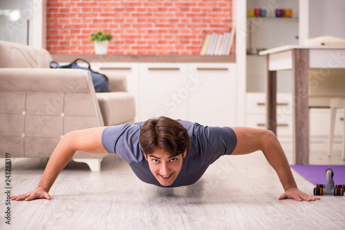 Young handsome man doing sport exercises at home 