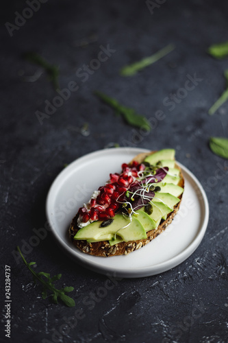 Avocado toast with seeds and sprouts on black table, close up.