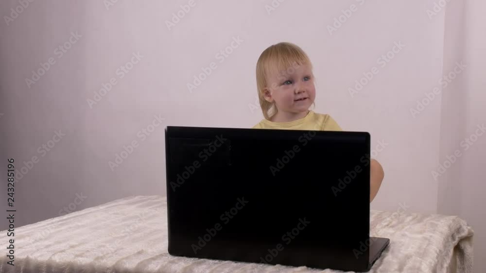 Little caucasian girl plays and plays with computer laptop, emotions, 4K Little caucasian girl plays and plays with computer laptop, emotions, 4K