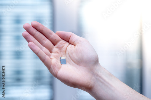 Young man is holding a tiny memory card in his hand, text space