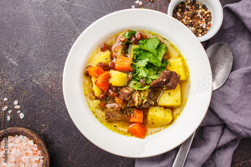 Traditional eintopf soup with meat, beans and vegetables in a white plate.