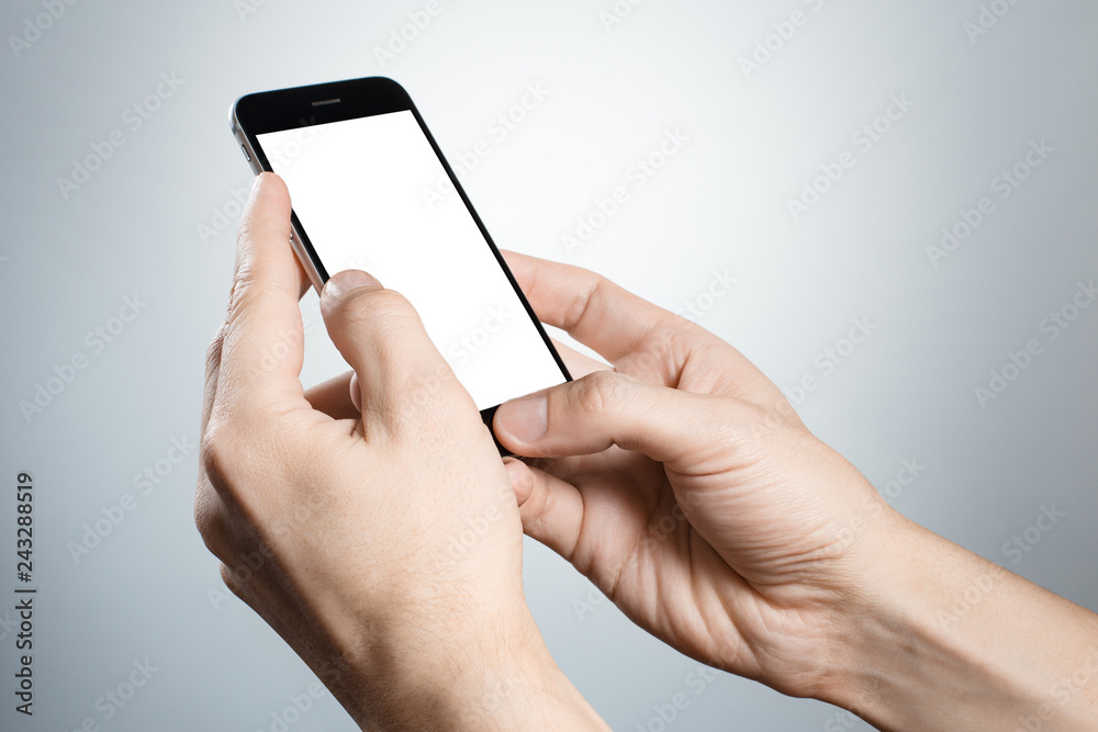 Hand holding and touching black smartphone on gray background