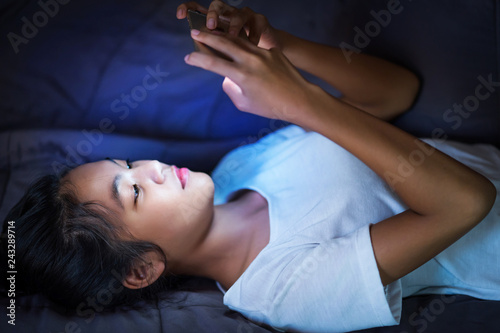 teen girl lying in bed at night and using smart phone
