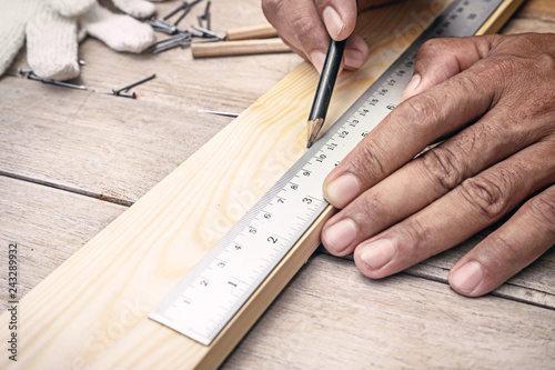 close up carpenter making measurements on the wooden plank