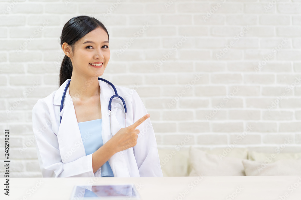 Closeup portrait of smiling beautiful female asian doctor standing with her arms crossed. Medicine representative concept on brick background.