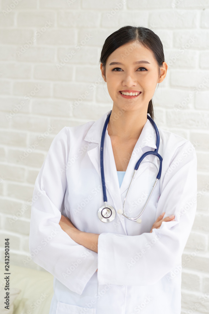 Closeup portrait of smiling beautiful female asian doctor standing with her arms crossed. Medicine representative concept on brick background. Closeup portrait of smiling beautiful female asian doctor standing with her arms crossed. Medicine representative concept on brick background.