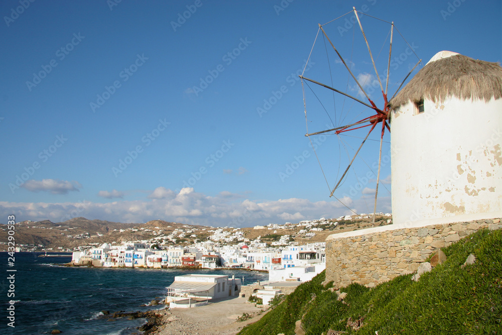 Traditinal windmill on the hillside with whitewashed homes in the background, Mykonos town, Cyclades, Greece.