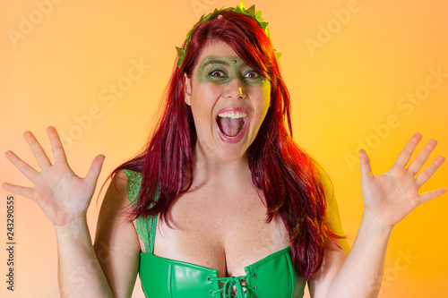 Carnaval Brazil. Portrait of latin redheaded woman and green makeup mask. Colorful background. Carnival concept, fun and party.