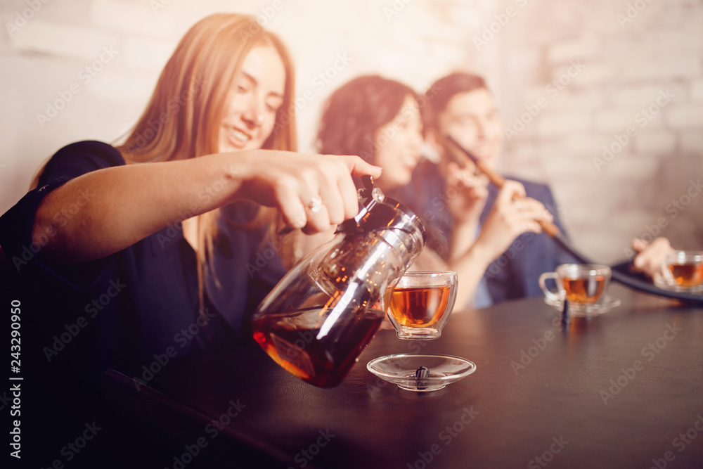 Group of friends man women met in cafe, smoking shisha hookah, drinking tea, chatting