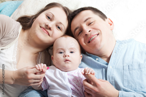 Family concept - baby with dad and mom. Portrait of happy young parents with baby in the bed at home.