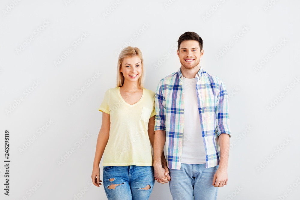 people and relationships concept - happy couple holding hands over white wall background people and relationships concept - happy couple holding hands over white wall background