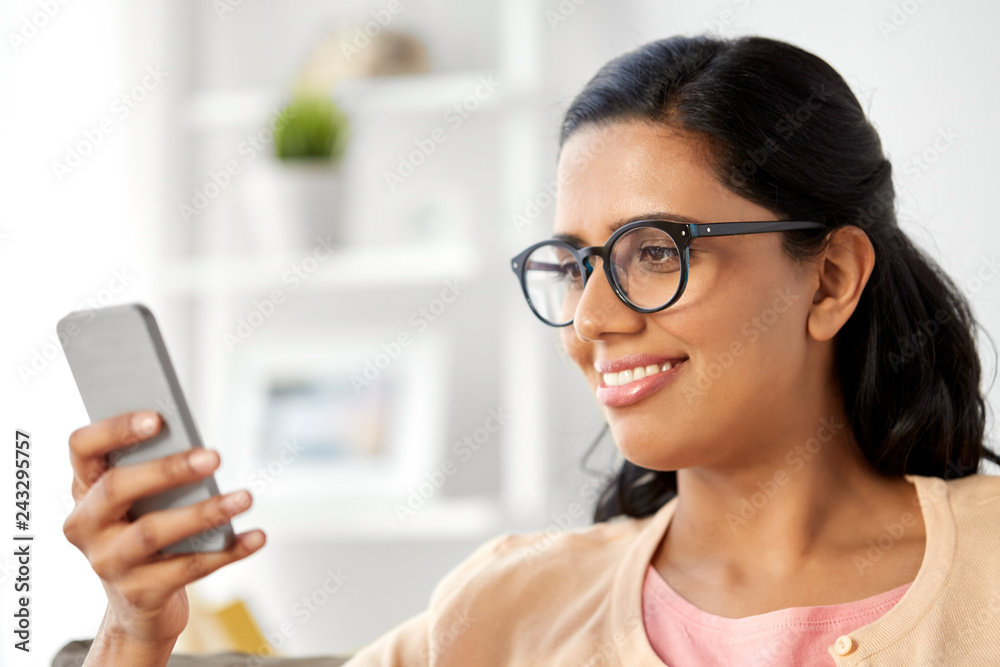 people and technology concept - happy indian woman using smartphone at home people and technology concept - happy indian woman using smartphone at home