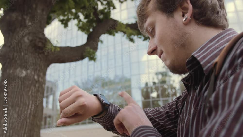 Young man using a smart watch, checking the message looking time and weather. Businessman using his smart watch app. Close-up hands. Time, business and digital technology concept. Young man using a smart watch, checking the message looking time and weather. Businessman using his smart watch app. Close-up hands. Time, business and digital technology concept.