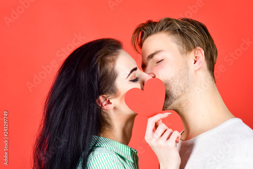 Romantic kiss concept. Couple in love kissing and hide lips behind heart card. Sensual kiss of lovely couple close up. Man and woman romantic kiss. Love and foreplay. Celebrate valentines day