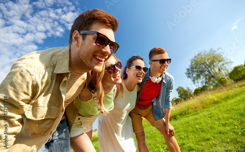 leisure, people and friendship concept - happy teenage friends laughing outdoors in summer