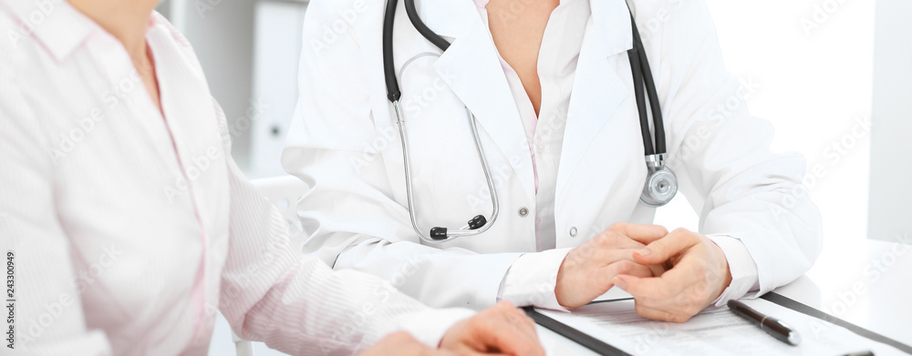 Doctor and patient talking in hospital office while sitting at the desk. Health care and client service in medicine Doctor and patient talking in hospital office while sitting at the desk. Health care and client service in medicine