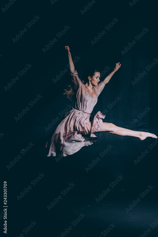 Ballerina on a black background make a jump