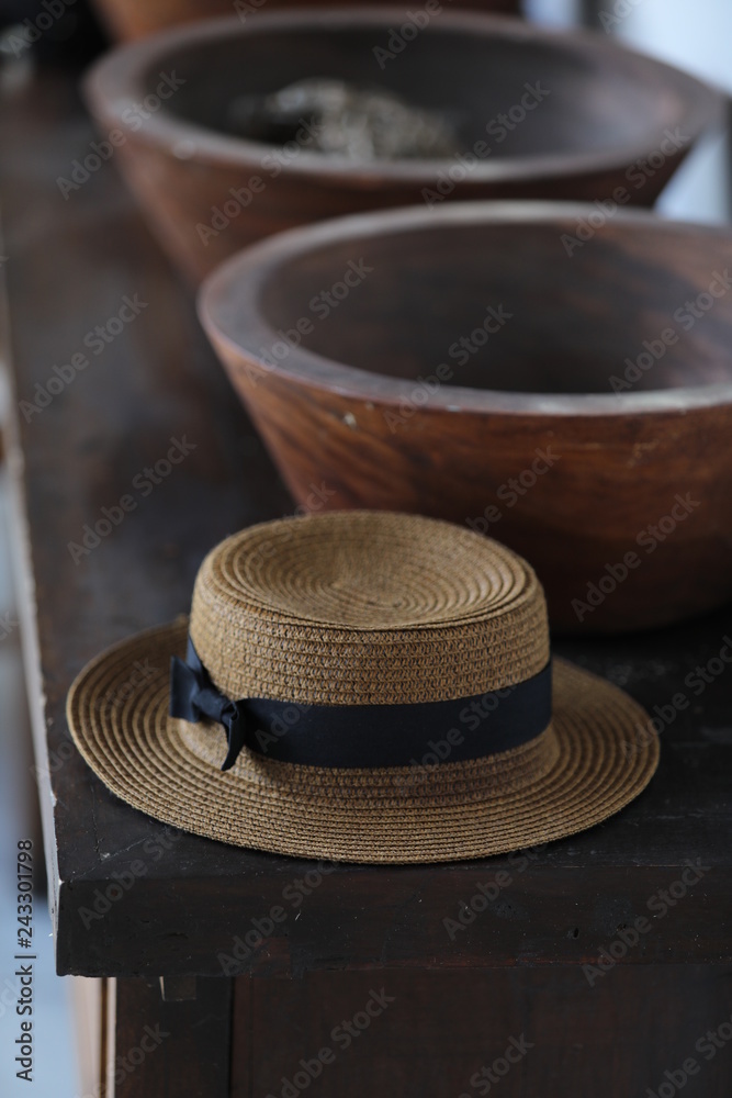 Straw hat with a bow is lying on a table near the bowl