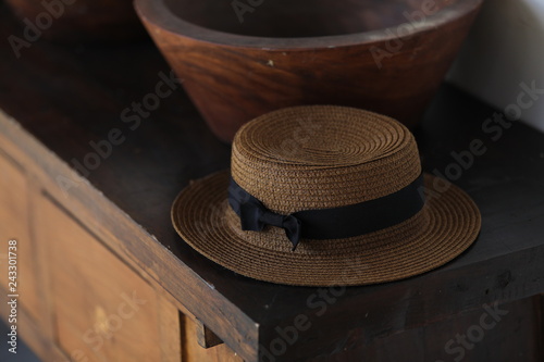 Straw hat with a bow is lying on a table near the bowl photo