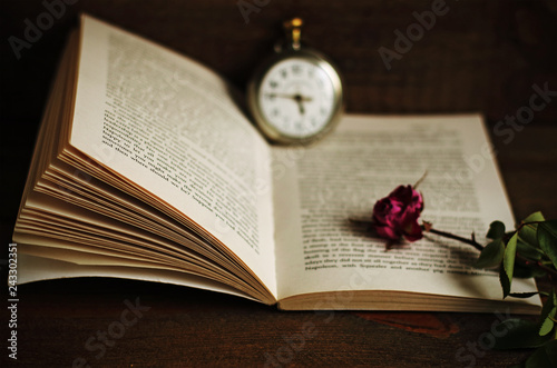 Book, magnifying glass, old pocket clock and withered rose