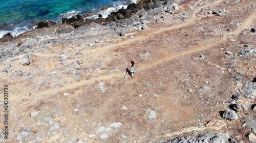 Aerial woman walk along on deserted sea shore at hot summer day, Crete photo