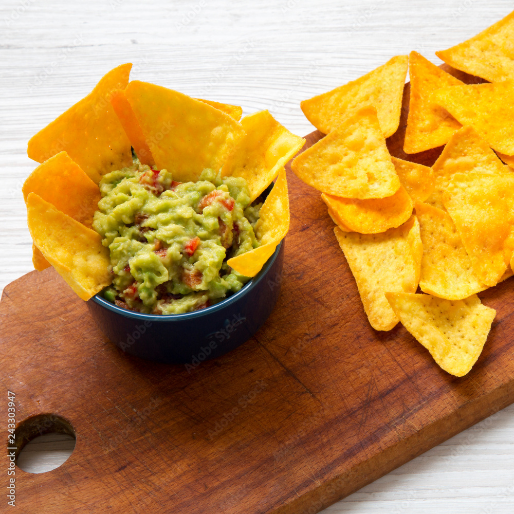 Traditional mexican guacamole with corn nachos on rustic wooden board, side view. Traditional mexican guacamole with corn nachos on rustic wooden board, side view.