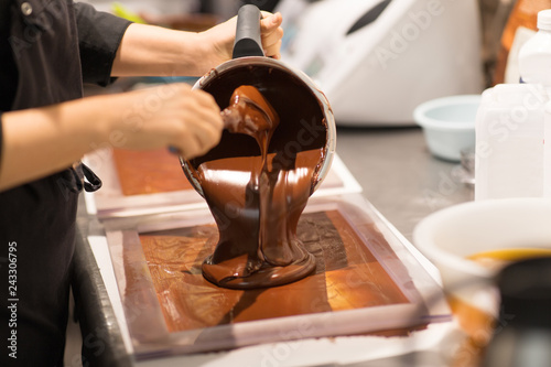 Photos production, cooking and people concept - confectioner filling mold with chocolat