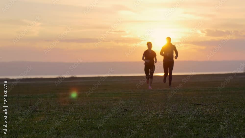 Group of runners training outdoors exercising at sunset on amazing nature landscape. Fit athletic family, man and woman working out for marathon run outside. Couple, male and female sport. Group of runners training outdoors exercising at sunset on amazing nature landscape. Fit athletic family, man and woman working out for marathon run outside. Couple, male and female sport.