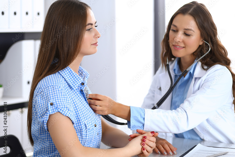 Obraz premium Doctor with a stethoscope in the hand examining her female patient. Health care, cardiology and medicine concepts
