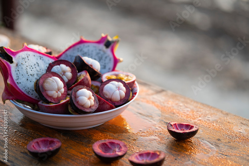 A plate of mangosteens with dragonfruit on the table 