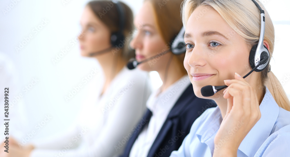 Call center. Group of operators at work. Focus at blonde business woman in headset Call center. Group of operators at work. Focus at blonde business woman in headset