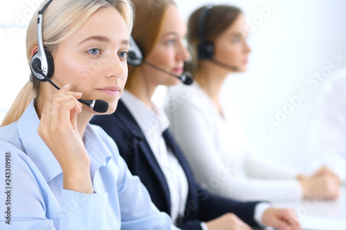 Call center. Group of operators at work. Focus at blonde business woman in headset