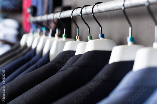 row of jackets on hangers in men clothing store