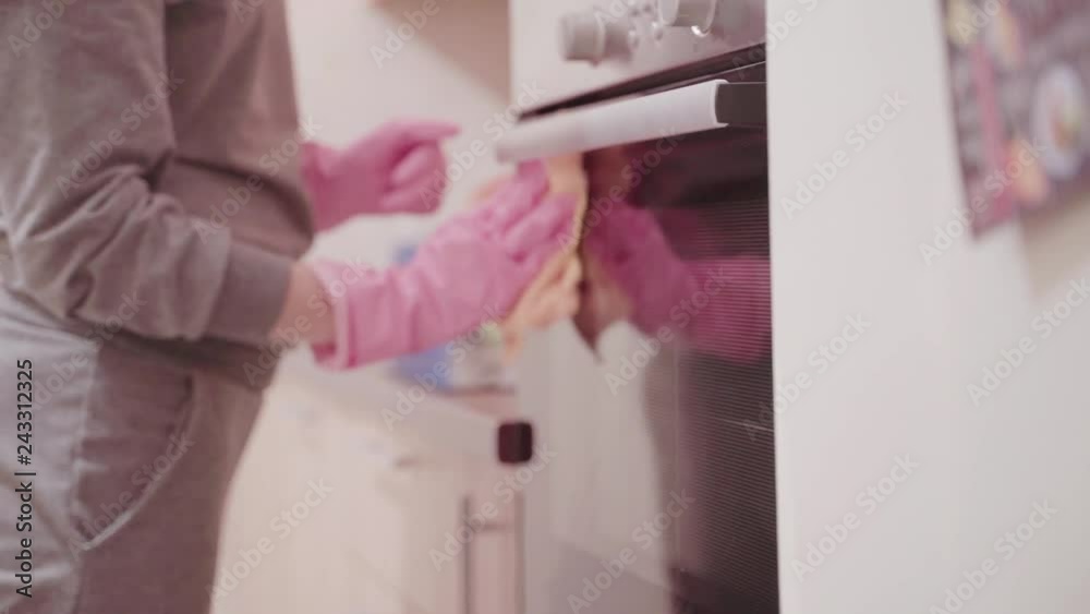 Closeup of young woman in pink rubber gloves cleaning electric oven. Closeup of young woman in pink rubber gloves cleaning electric oven.