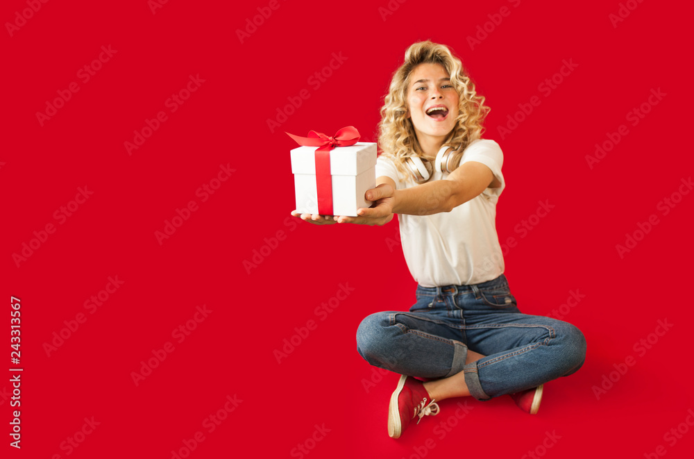 Beautiful girl with a white gift in her hands on a red isolated background in full growth.Valentine's Day concept Beautiful girl with a white gift in her hands on a red isolated background in full growth.Valentine's Day concept