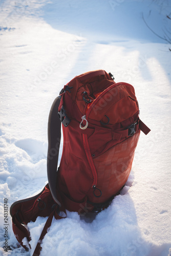 Small red backpack stands on the white snow