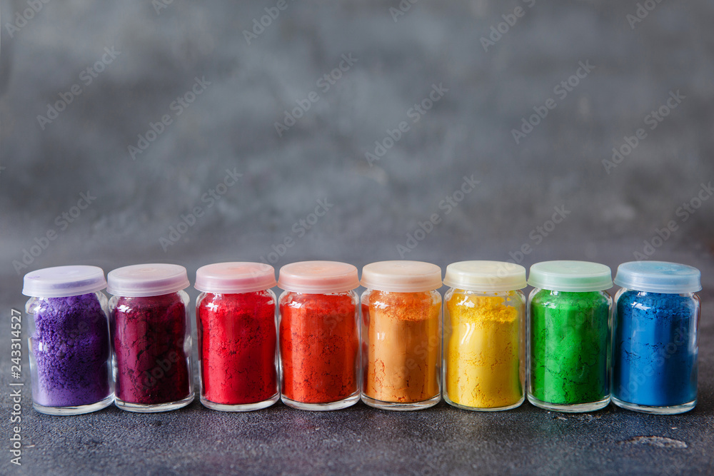 Bright colourful powdered pigments in glass bottles for Indian holi festival on dark slate background, copy space Bright colourful powdered pigments in glass bottles for Indian holi festival on dark slate background, copy space