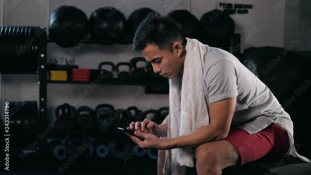 Tired asian korean young man using his mobile in the gym. Student boxer with phone after workout voice message ai application sport audio towel Tired asian korean young man using his mobile in the gym. Student boxer with phone after workout voice message ai application sport audio towel