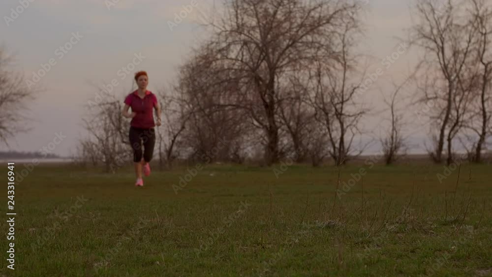 Young woman running at sunrise. Fitness runner girl training outdoors at sunset on amazing landscape nature. Fit athletic female working out for marathon, run outside. Sport and health. Slow motion. Young woman running at sunrise. Fitness runner girl training outdoors at sunset on amazing landscape nature. Fit athletic female working out for marathon, run outside. Sport and health. Slow motion.