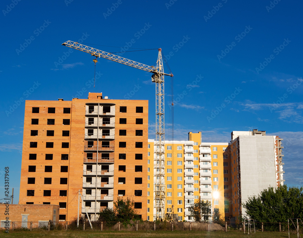 Construction of new apartment building. Facade of unfinished brick multistory building with crane and new dwelling on the background