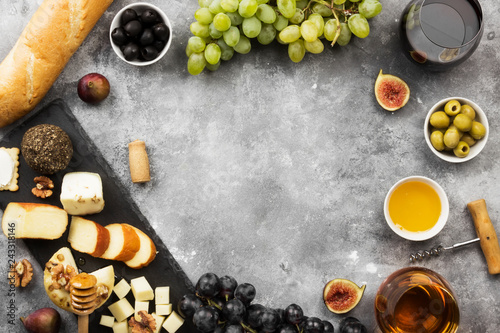 Snacks with wine - various types of cheeses, figs, nuts, honey, grapes, bread on a gray background. Top view, copy space. Food background