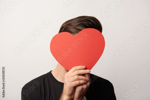 man in black with obscure face and empty paper cut heart card isolated on grey